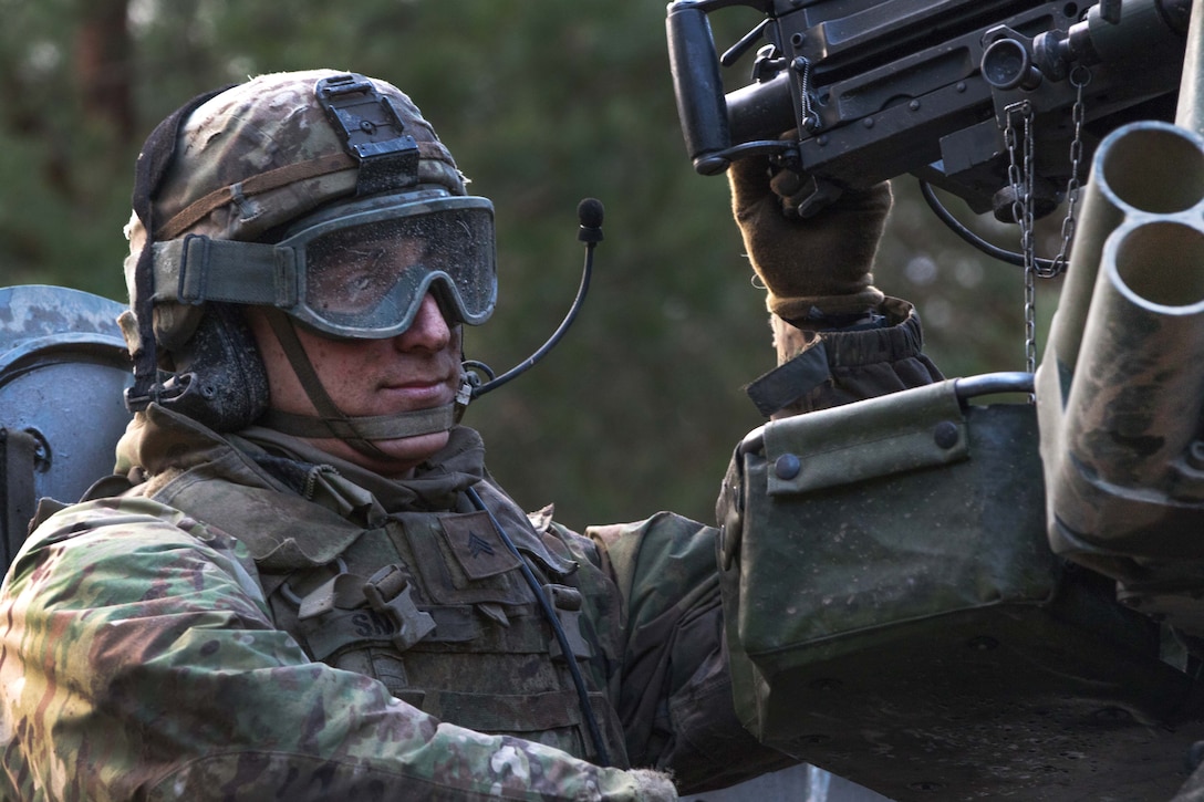 A soldier sits in the gunner's seat of a Stryker vehicle.