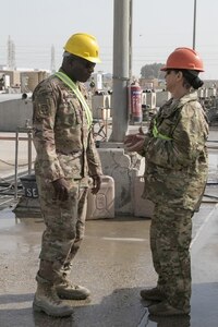 Sgt. Maj. Andre Lawhorn, 35th Infantry Division chemical, biological, radiological and nuclear sergeant major, takes a moment to talk to 35th Inf. Div. materials handler Staff Sgt. Mary Hunt about wash rack operations at Kuwait Naval Base.