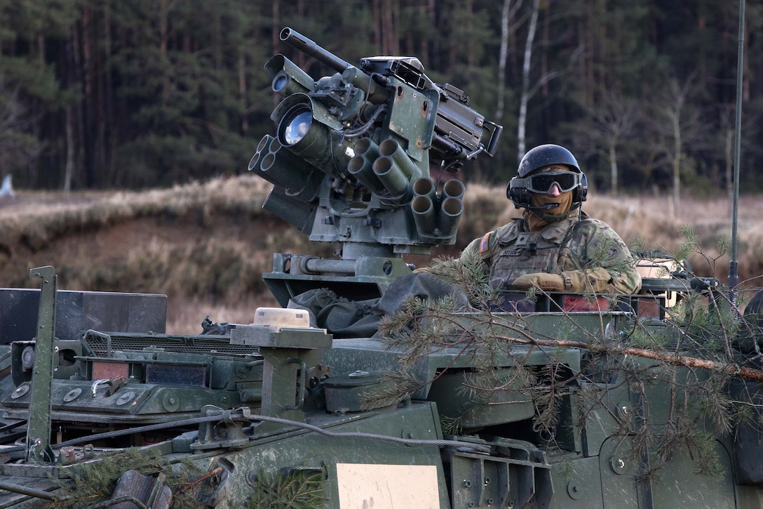 A soldier sits in a Stryker vehicle gunner's seat manning a .50-caliber machine gun.