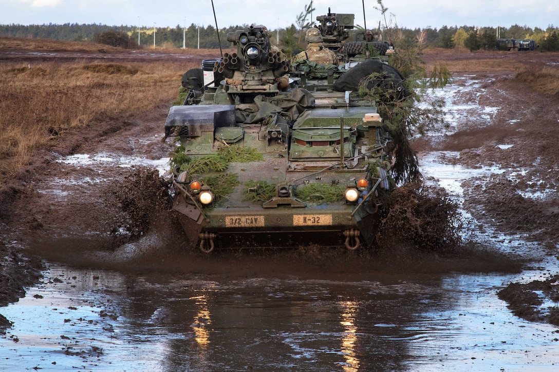 Soldiers maneuver an M1126 Stryker vehicle through a mud pit.