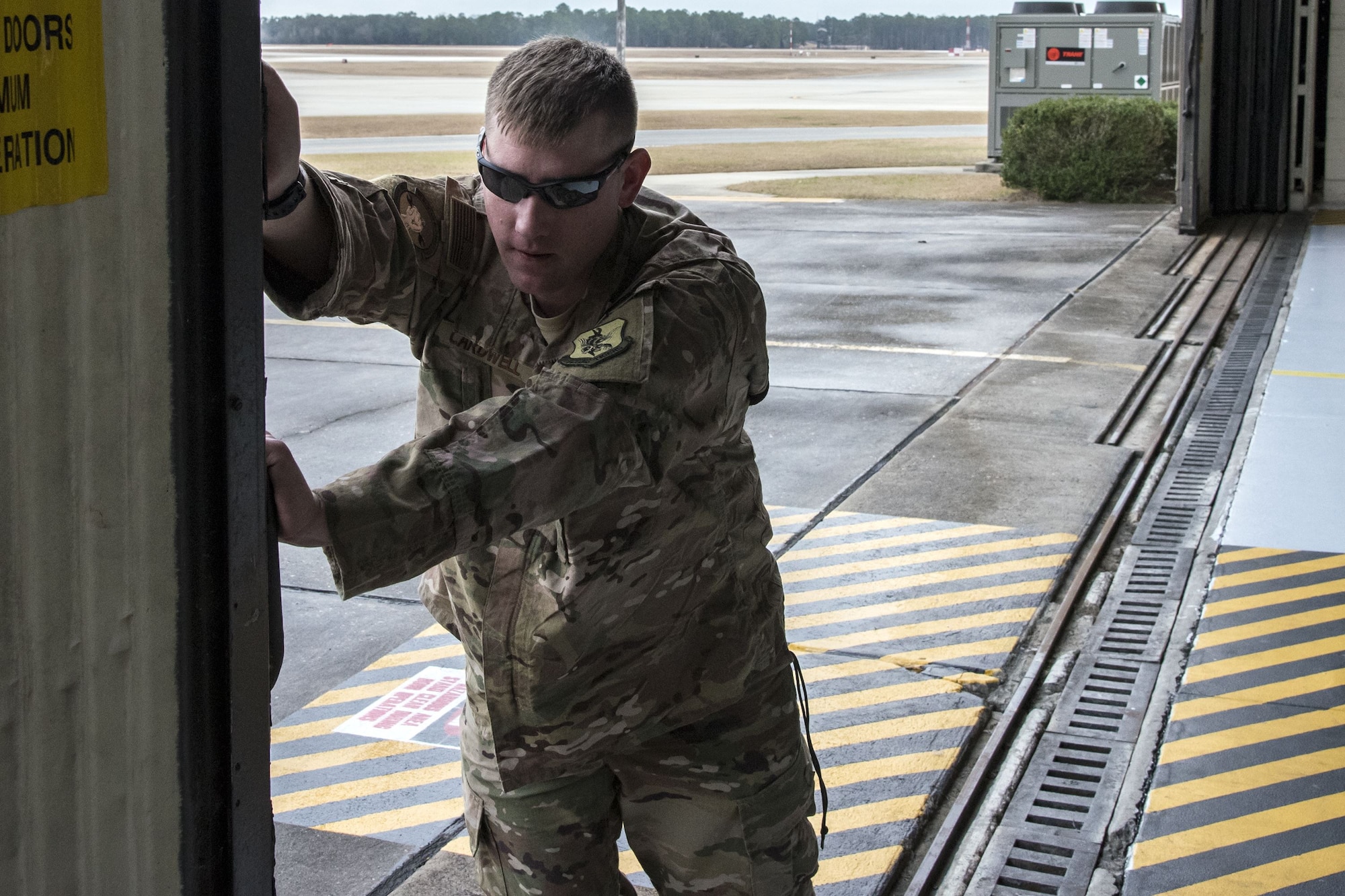 Tech Sgt. Jesse Cardwell, 723d Aircraft Maintenance Squadron (AMXS) HH-60G Pave Hawk crew chief, pushes a hangar door open, Jan. 22, 2018, at Moody Air Force Base, Ga. From 16-25 Jan., Airmen from the 723d AMXS performed 216 hours of maintenance on an HH-60 after it returned to Moody following 350 days of depot maintenance at Naval Air Station (NAS) Jacksonville. While at NAS Jacksonville, the HH-60 underwent a complete structural overhaul where it received new internal and external components along with repairs and updated programming. (U.S. Air Force photo by Airman Eugene Oliver)