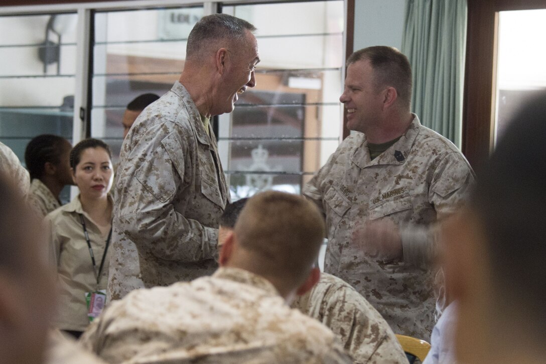The chairman of the Joint Chiefs of Staff laughs with a Marine during a visit to a military base in Australia.