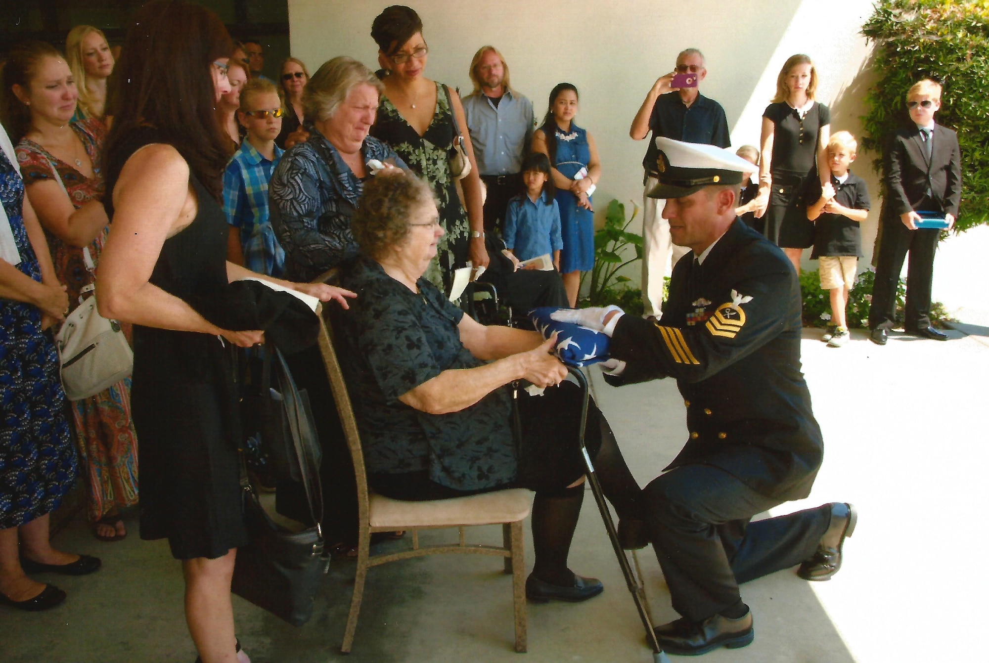 Intelligence Specialist Chief Petty Officer Paul Baumgartner hands a folded flag to his grandmother, Betty Lou Baumgartner, after acting as pallbearer alongside his five brothers at their grandfather Roy's funeral in June, 2017.