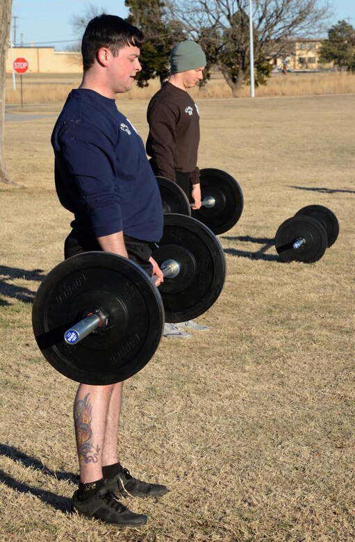 Senior Airman Jourdan Campbell and Staff Sgt. Brandon Gourley perform deadlifts as part of their interval exercises during PT at Airman Leadership School.