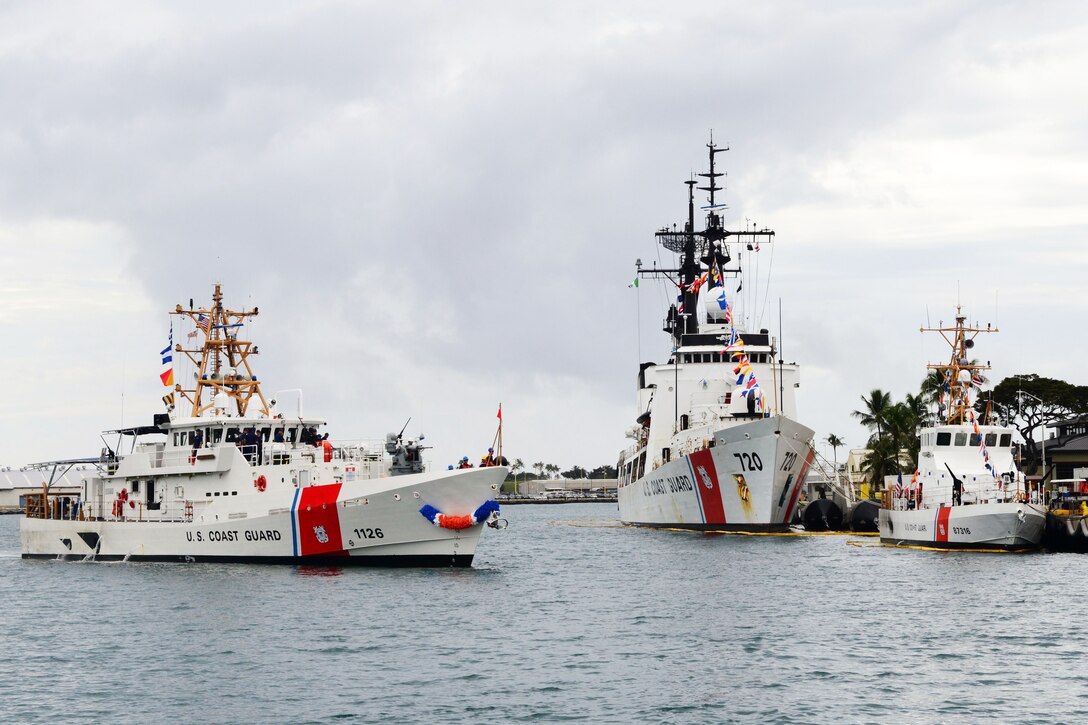 Three Coast Guard ships float together at a dock in Honolulu.