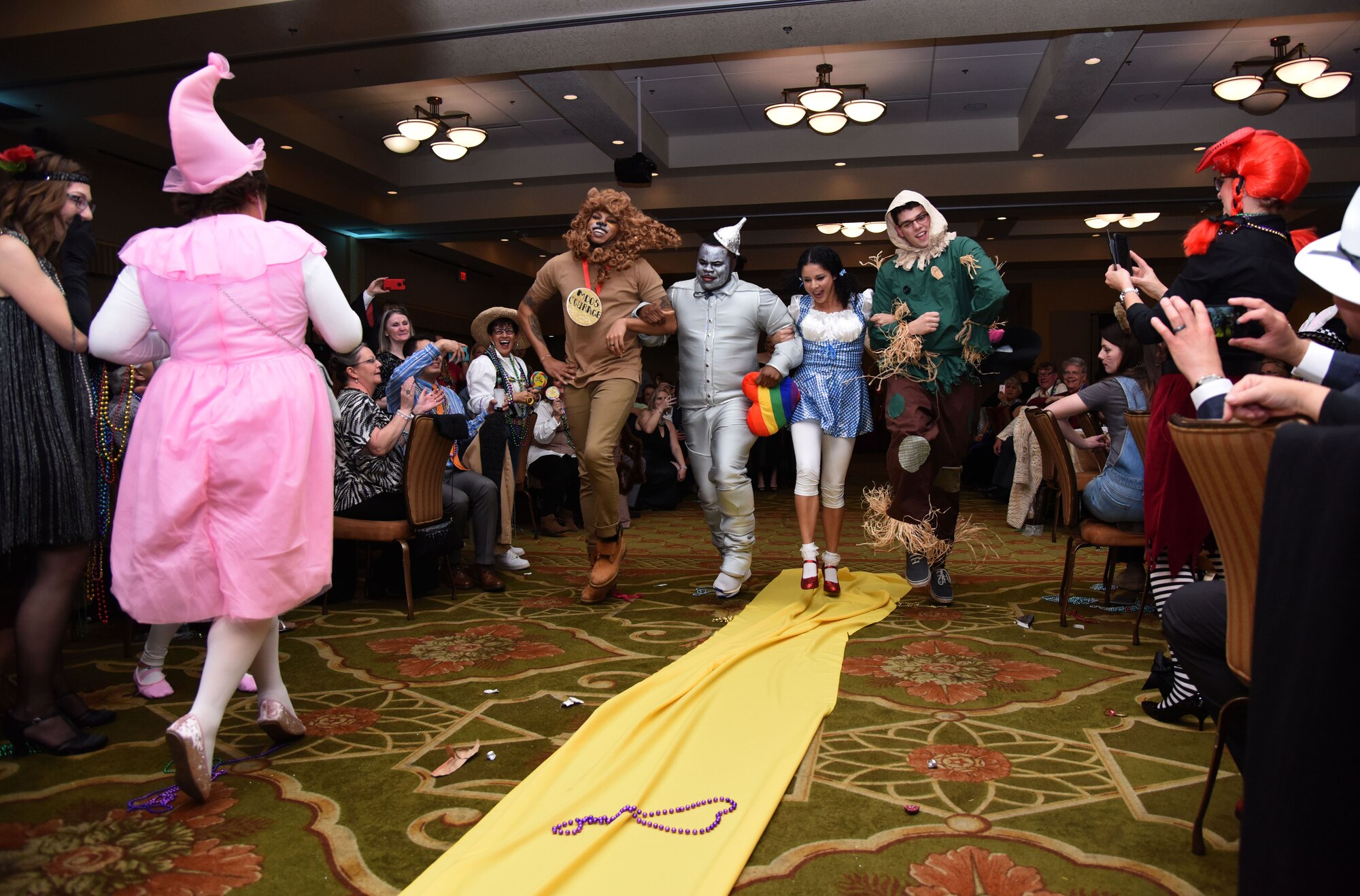 Members of the 81st Medical Operations Squadron portray the cast of The Wizard of Oz as they dance down the aisle during a Mardi Gras float contest at the 30th Annual Krewe of Medics Mardi Gras Ball at the Bay Breeze Event Center Feb. 3, 2018, on Keesler Air Force Base, Mississippi. The Krewe of Medics hosts a yearly ball to give Keesler Medical Center personnel a taste of the Gulf Coast and an opportunity to experience a traditional Mardi Gras. The theme for this year's ball was Read It-Be It. The 81st MDOS won first place in the float contest. (U.S. Air Force photo by Kemberly Groue)