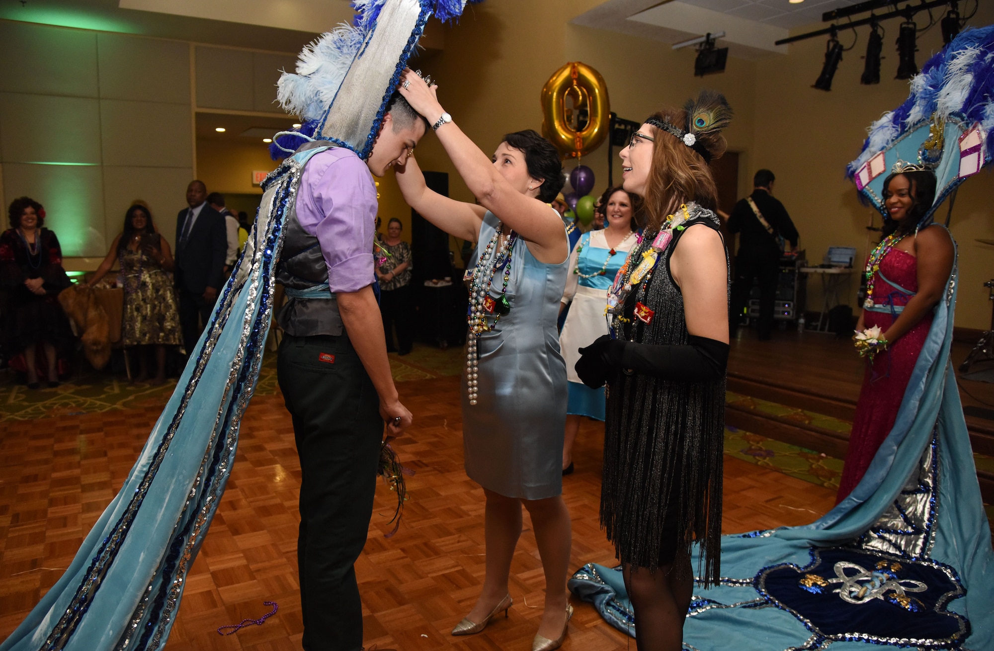 Col. Jeannine Ryder, 81st Medical Group commander, crowns Airman John Shelby, 81st Diagnostic and Therapeutics Squadron, as the 2018 Krewe of Medics king as Chief Master Sgt. Julie Bottroff, 81st MDG superintendent, looks on during the 30th Annual Krewe of Medics Mardi Gras Ball at the Bay Breeze Event Center Feb. 3, 2018, on Keesler Air Force Base, Mississippi. The Krewe of Medics hosts a yearly ball to give Keesler Medical Center personnel a taste of the Gulf Coast and an opportunity to experience a traditional Mardi Gras. The theme for this year's ball was Read It-Be It. (U.S. Air Force photo by Kemberly Groue)