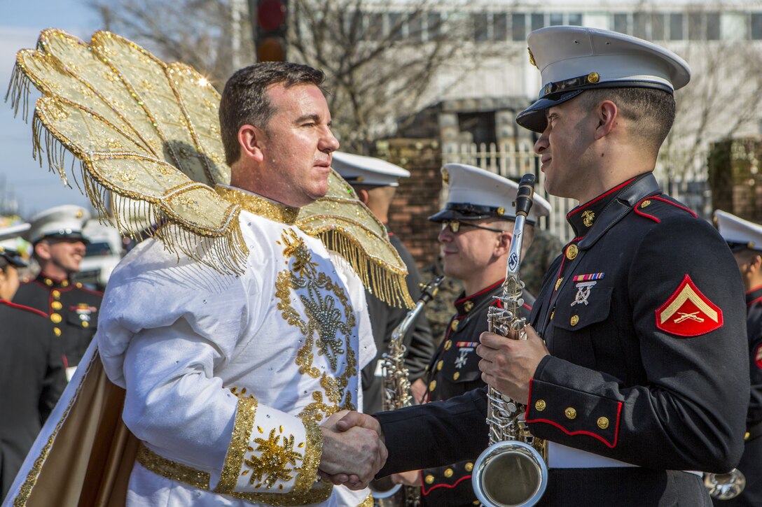 A Marine musician shakes hands with a member of a long-standing Mardi Gras parade.