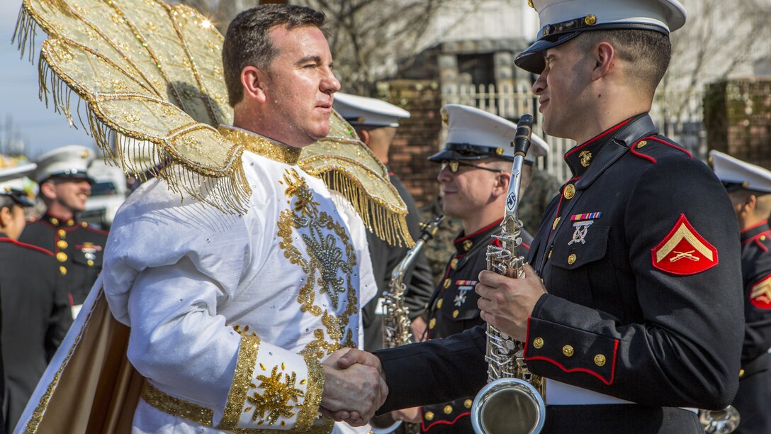 A Marine musician shakes hands with a member of a long-standing Mardi Gras parade.