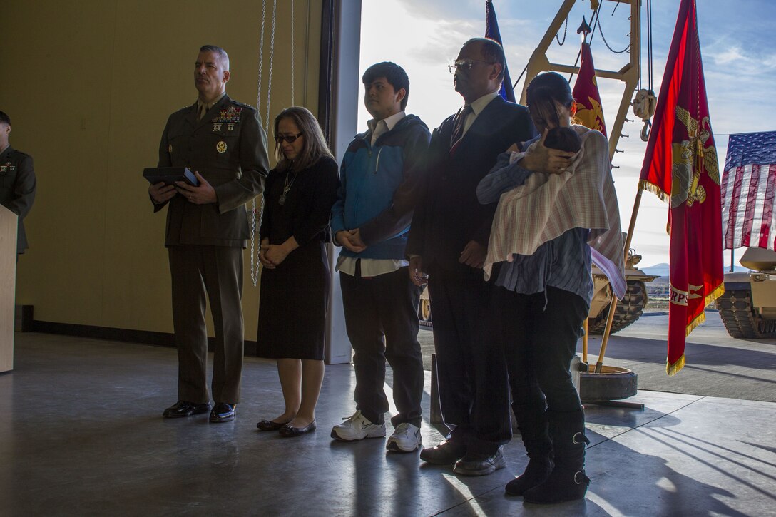Major General William F. Mullen III, Commanding General, Marine Air Ground Task Force Training Command, Marine Corps Air Ground Combat Center, participates in an award ceremony with the family of Staff Sgt. Enrico Antonio Rojo at a memorial for Staff Sgt. Rojo aboard the Marine Corps Air Ground Combat Center, Twentynine Palms, Calif., Jan. 21, 2018. Staff Sgt. Rojo was awarded a Navy and Marine Corps Medal for attempting to help the victim of a car accident on December 16, 2016.(U.S. Marine Corps photo by Pfc. Rachel K. Porter)