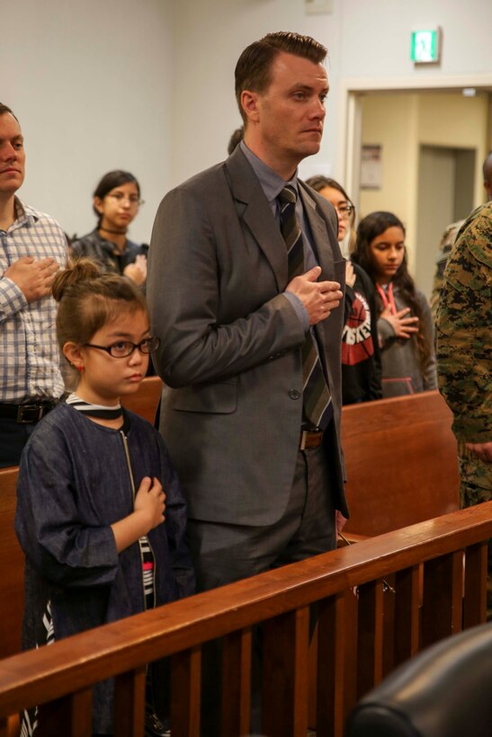 A father and daughter recite the Pledge of Allegiance during a naturalization ceremony Jan. 31 aboard Camp Foster, Okinawa, Japan. Families and friends gathered to support their loved ones in taking their final step towards becoming U.S. citizens. Eleven candidates from seven different countries stood in front of their families, raised their right hand and repeated the Oath of Allegiance to obtain their citizenship. (U.S. Marine Corps photo by Pfc. Nicole Rogge)