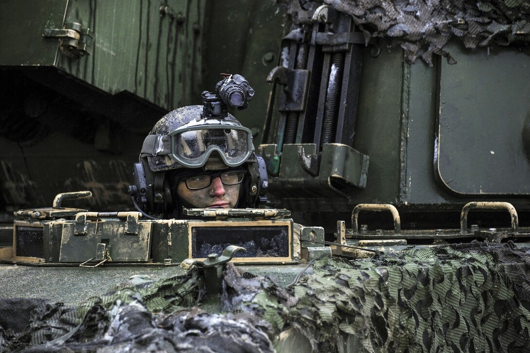 A soldier looks out from the driver's hatch of a howitzer.