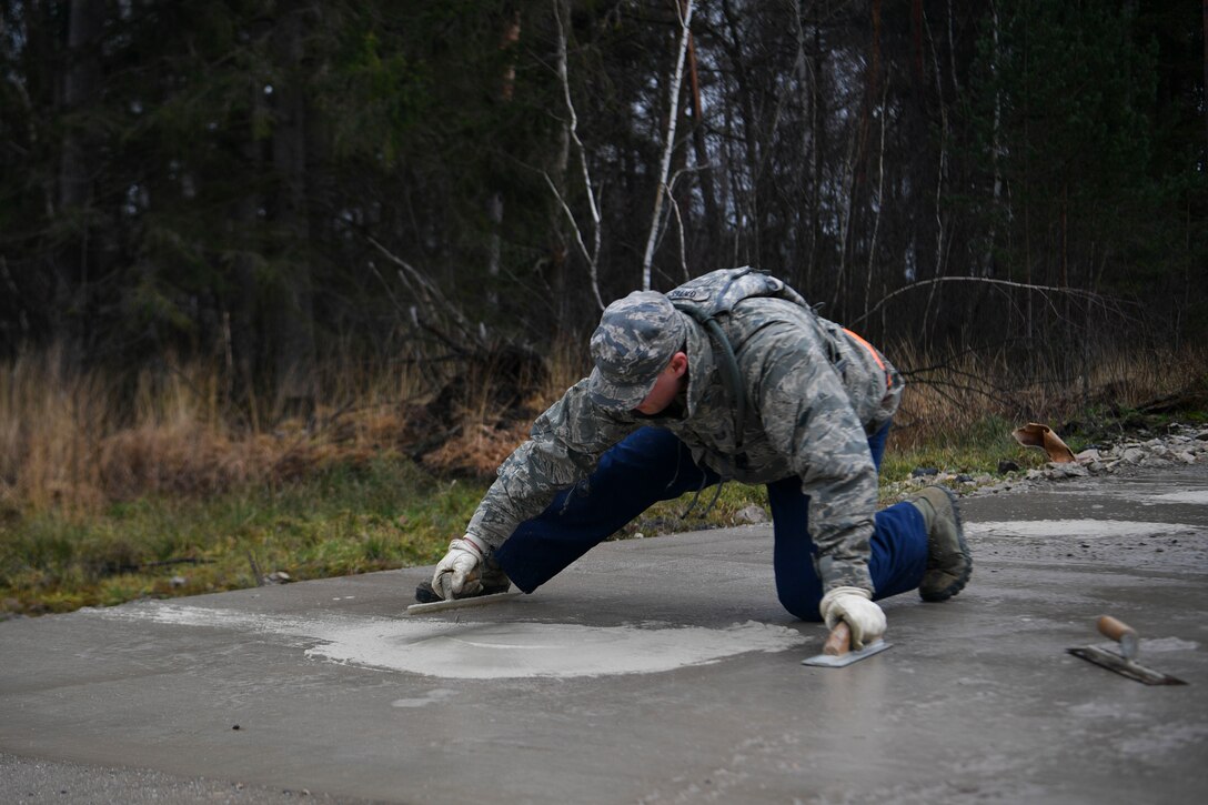 U.S. Air Force Tech. Sgt Corey Gates, 773rd Civil Engineer Squadron heating, ventilation, and air conditioning craftsman, fills a small hole with quick drying cement during a Rapid Airfield Damage Repair training exercise on Ramstein Air Base, Germany, Jan. 25, 2018. Airmen were placed into predesignated roles based on career field to complete the task of repairing and reopening the simulated airfield. (U.S. Air Force photo by Senior Airman Devin M. Rumbaugh)