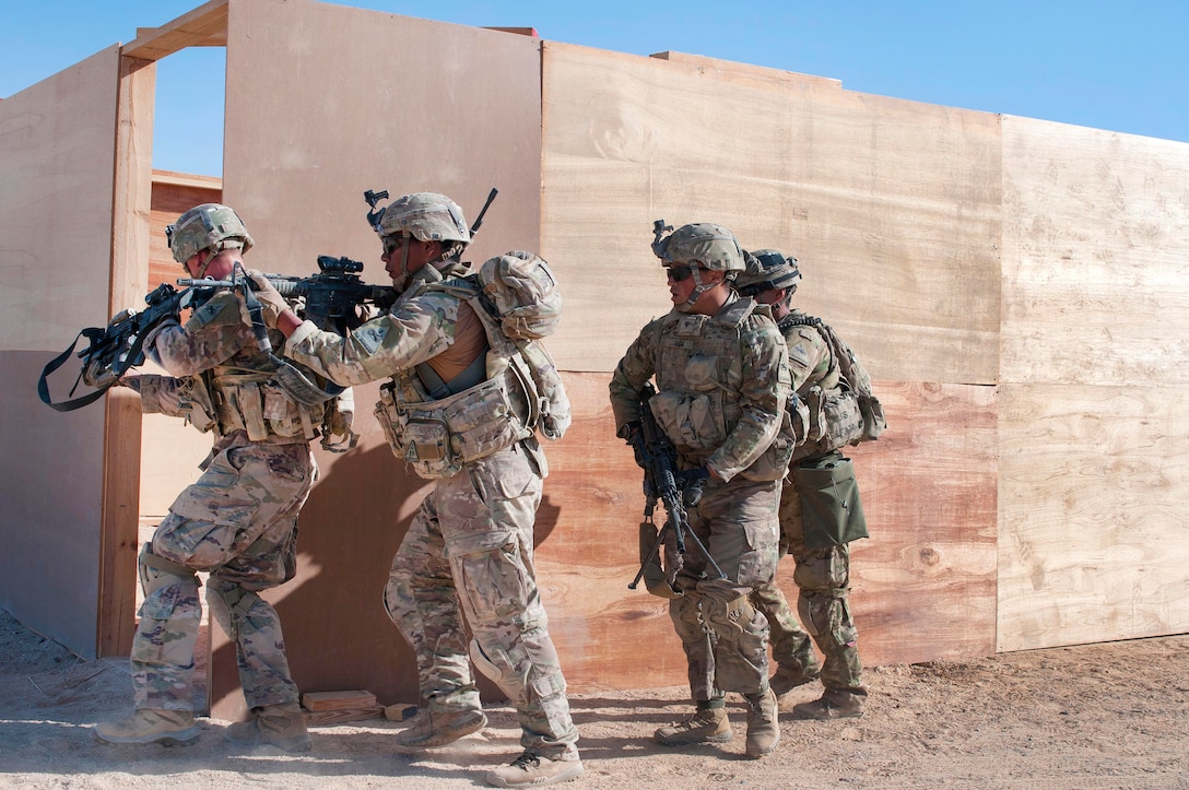 Soldiers with rifles assault a building entrance.