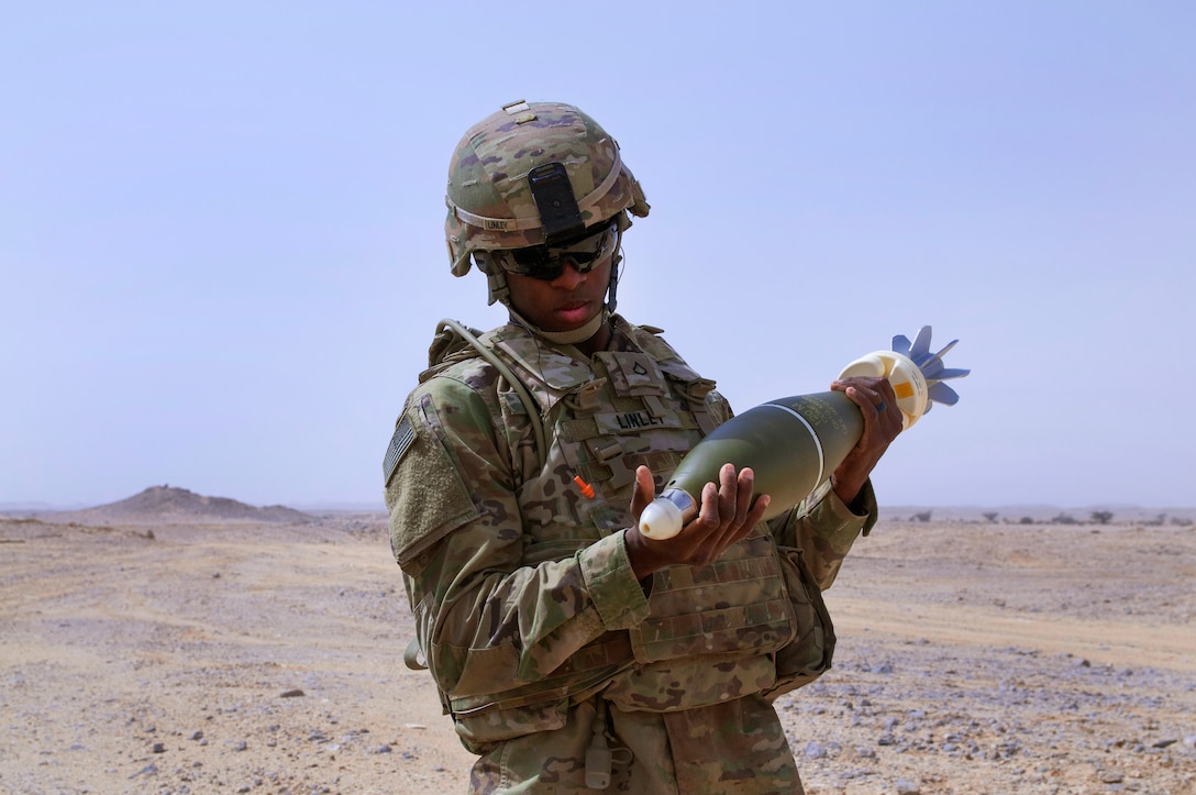 A soldier holds a 120 mm mortar round.