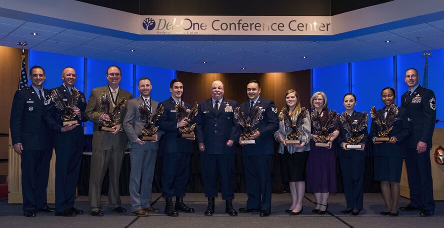 Annual award winners from the 436th Airlift Wing, Dover Air Force Base, Del., line up on stage for a group photo with Col. Ethan Griffin, 436th AW commander (far left); Master Sgt. Israel Del Toro, guest speaker (center); and Chief Master Sgt. Michael Zimmerman, 436th AW interim command chief (far right); at the conclusion of the 2017 Annual Awards Ceremony, Feb. 3, 2018, in the convention center at Delaware Technical Community College. Fifty-two superheroes from the 436th AW competed to be recognized as "best-of-the-best" and receive the coveted eagle trophy in their respective category. (U.S. Air Force photo by Roland Balik)