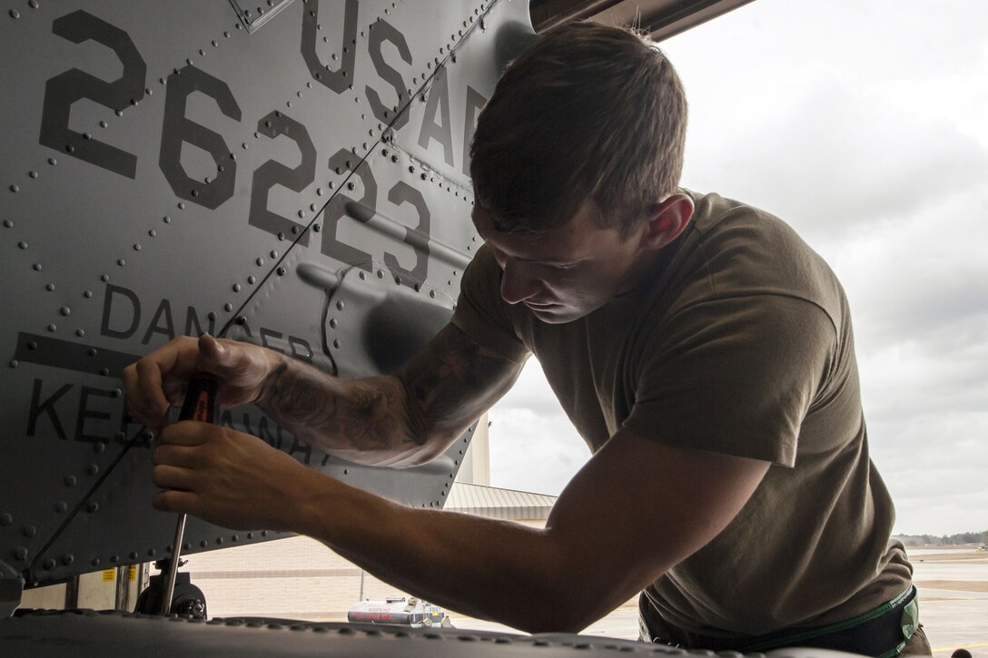 An airman tightens a bolt on a helicopter.
