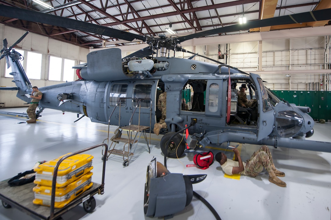 Airmen conduct exterior maintenance on a helicopter.