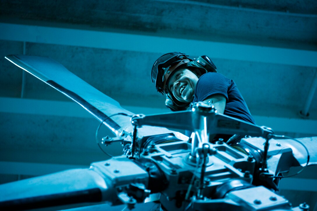 A sailor conducts maintenance on a helicopter tail rotor.