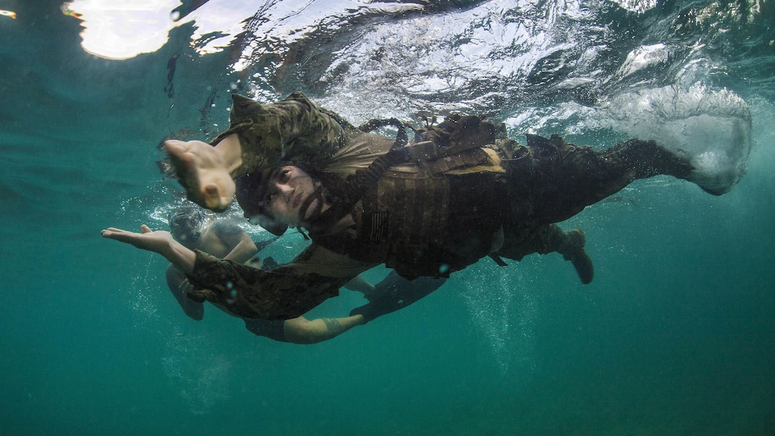 A sailor does a breaststroke-type motion under aqua water.