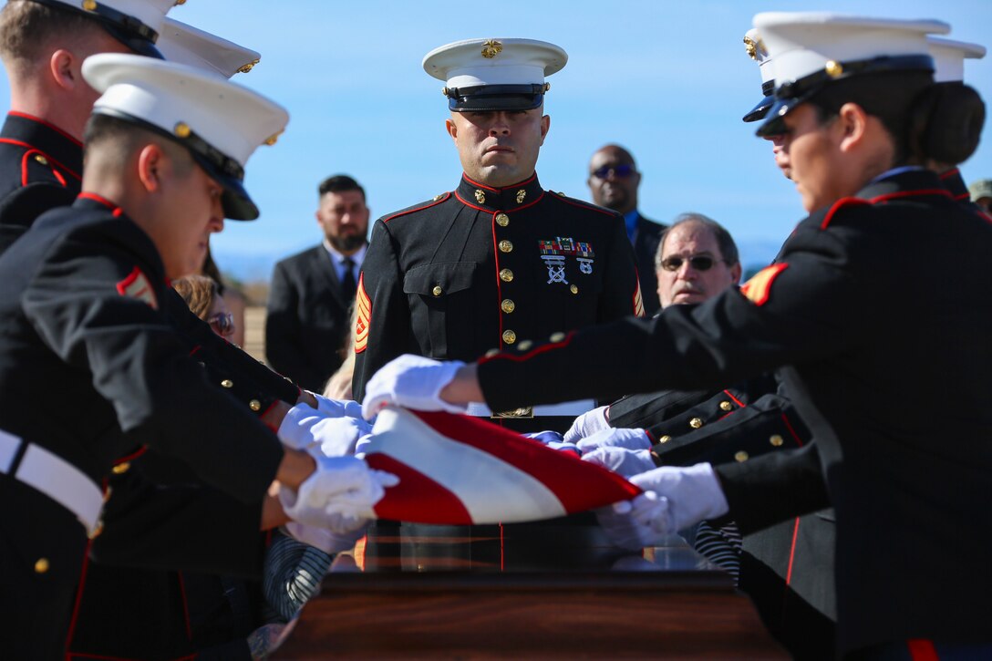 Gunnery Sgt. Manuel Martinez-Ortiz, company first sergeant, Alpha Company, Headquarters Battalion, Marine Corps Air Ground Combat Center, Twentynine Palms, Calif., watches over the pall bearers as they fold a flag over the coffin of Ray V. Wilburn, retired Sgt. Major, at Twentynine Palms Public Cemetery, Jan. 13, 2018. Wilburn served 32 years of honorable and faithful service to the United States Marine Corps, taking part in World War 2, the Korean War and the Vietnam War. (U.S. Marine Corps photo by Lance Cpl. Isaac Cantrell)