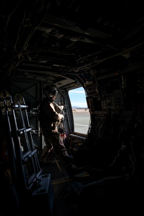 A Marine crew chief with 3rd Marine Aircraft Wing looks out the window of the an MV-22 Osprey at the Air Combat Element landing strip at Marine Corps Air Ground Combat Center, Twentynine Palms, Calif., Jan. 18, 2018, as a part of Integrated Training Exercise 2-18. The purpose of ITX is to create a challenging, realistic training environment that produces combat-ready forces capable of operating as an integrated MAGTF. (U.S. Marine Corps Photo by Pfc. William Chockey)