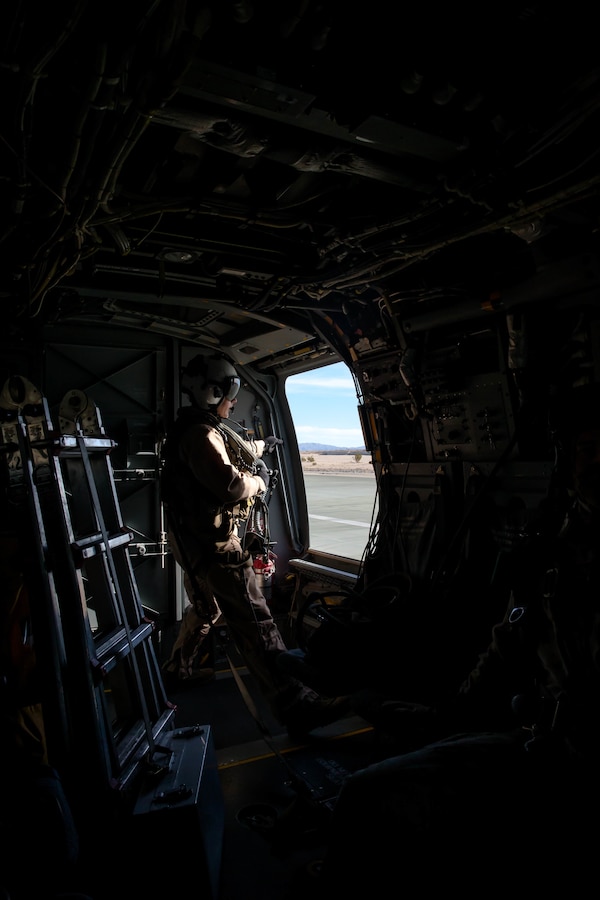 A Marine crew chief with 3rd Marine Aircraft Wing looks out the window of the an MV-22 Osprey at the Air Combat Element landing strip at Marine Corps Air Ground Combat Center, Twentynine Palms, Calif., Jan. 18, 2018, as a part of Integrated Training Exercise 2-18. The purpose of ITX is to create a challenging, realistic training environment that produces combat-ready forces capable of operating as an integrated MAGTF. (U.S. Marine Corps Photo by Pfc. William Chockey)