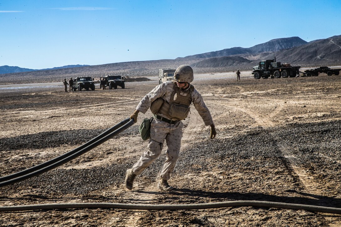 A Marine with Marine Wing Support Squadron 371 carries a jet fuel line to a Bell AH-1Z Viper at Marine Corps Air Ground Combat Center, Twentynine Palms, Calif., Feb. 4, 2018, as a part of Integrated Training Exercise 2-18. The purpose of ITX is to create a challenging, realistic training environment that produces combat-ready forces capable of operating as an integrated MAGTF. (U.S. Marine Corps Photo by Pfc. William Chockey)