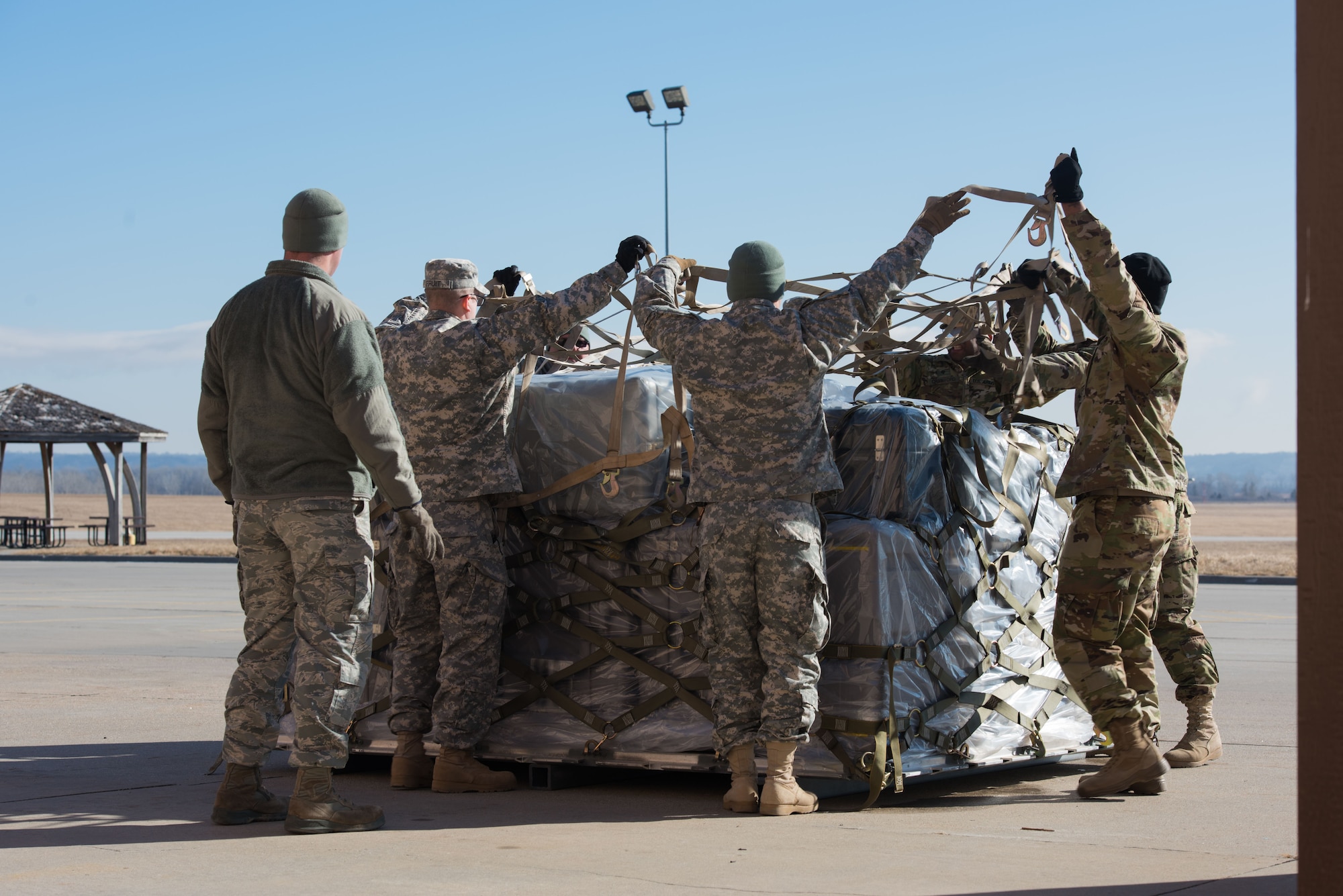 Soldiers from the U.S. Army Reserve 561st Regional Support Group, spread netting over a baggage pallet during a cargo preparation course at Offutt Air Force Base, Nebraska, Jan. 29, 2018. The Soldiers gained knowledge and skill in palletization, rolling stock, weighing, ways to protect and secure stock and the hazards to be aware of while working with air cargo. (U.S. Air Force photo by Senior Airman Jacob Skovo)