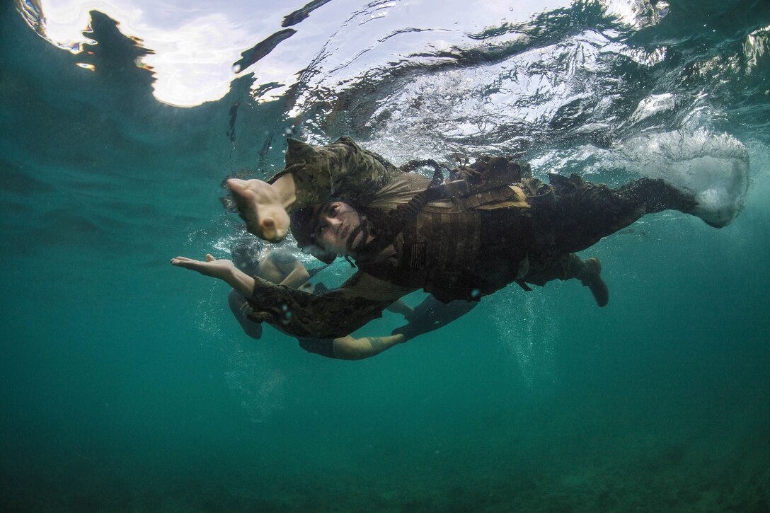 A sailor does a breaststroke-type motion under aqua water.