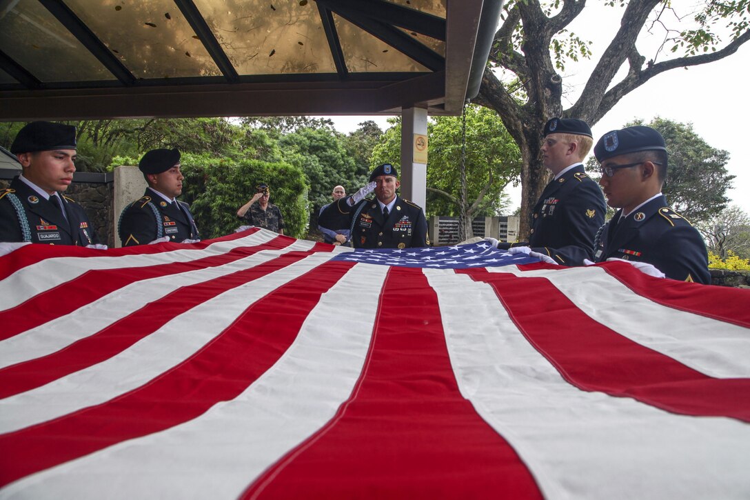 Soldiers hold up a large American flag.