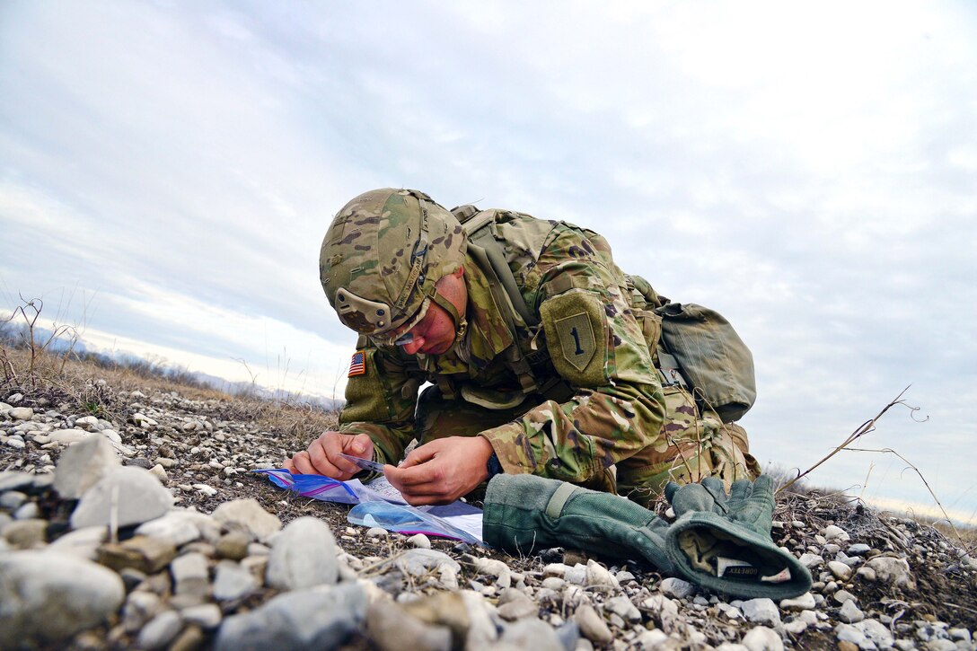 A paratrooper plots grid coordinates on his map.