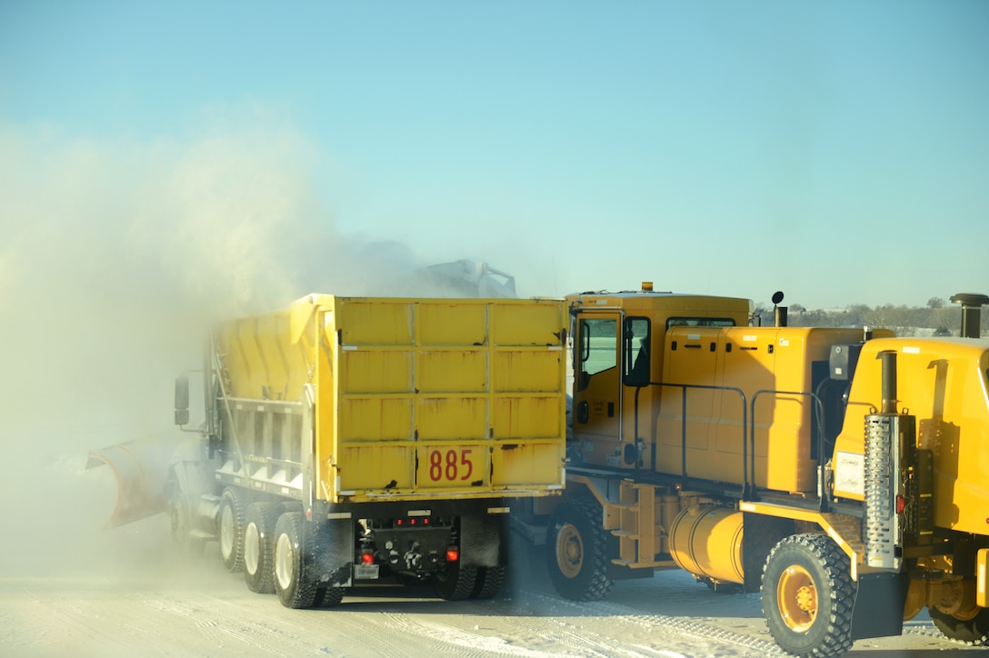 Air Force airmen and the maintenance crews operate snow removal vehicles to clear the snow off the flightline.