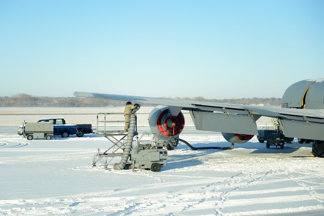 An Air Force airman de-ices and removes snow from an aircraft.