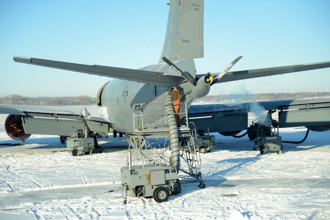 An Air Force airman de-ices and removes snow from an aircraft.