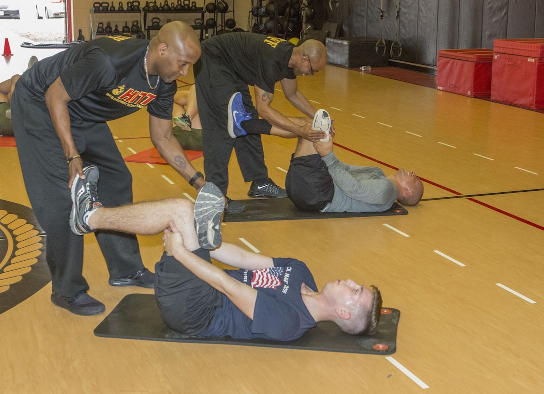 Christopher Harper,(left) High Intensity Tactical Training coordinator, Semper Fit, and Justin Roberts, (right)assistant HITT coordinator, Semper Fit, help Marines from U.S. Marine Corps Forces Command and Marine Air Group 49, Marine Medium Tiltrotor Squadron 774, 4th Marine Aircraft Wing, stretch during a HITT Level I instructor course at Hopkins Hall Gym aboard Camp Allen, in Norfolk, Va., Feb. 6. Instructors taught Marines about the four elements of HITT: athlete, combat, warrior and reload. Each program has a different focus and different workouts and exercises tailored to give the participant a way to achieve the desired outcome. (Official Marine Corps photo by Chris Jones/Released)