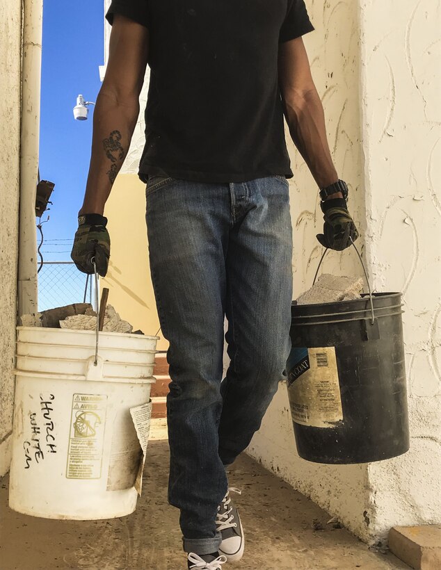 U.S. Marine Corps Cpl. Isaac D. Martinez, a strategic communication specialist assigned to Marine Corps Air Station (MCAS) Yuma’s Headquarters & Headquarters Squadron, moves buckets full of rubble from a torn-down shed at St. Thomas Yuma Indian Mission in Winterhaven, Calif., Feb. 3, 2018. The mission, located out in the local Yuma community, requested help in tearing down the shed so that renovations could be made to the building. (U.S. Marine Corps photo taken by Lance Cpl. Joel Soriano)