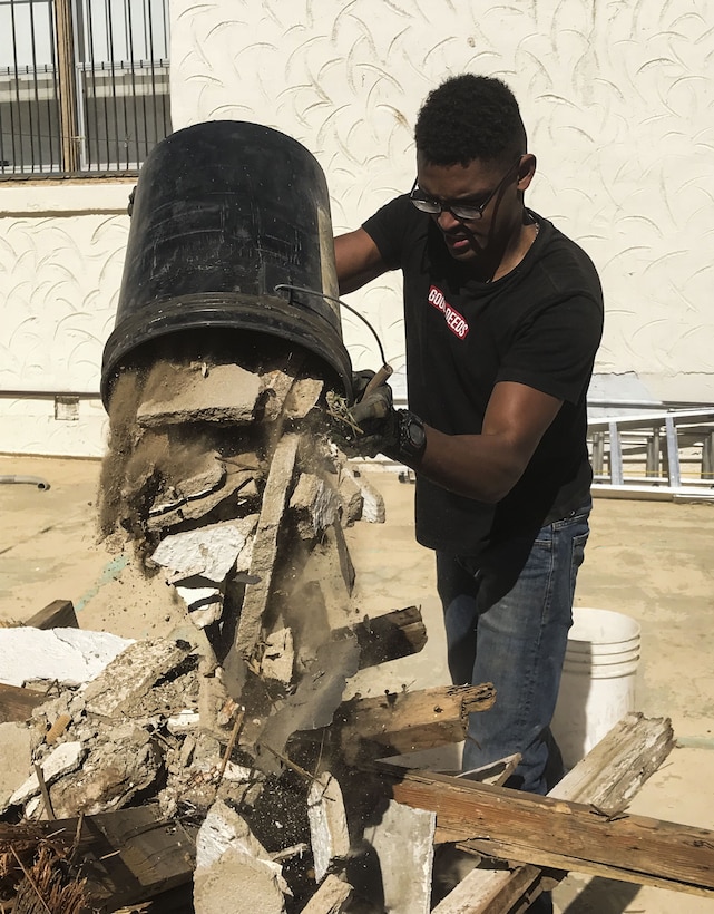 U.S. Marine Corps Cpl. Isaac D. Martinez, a strategic communication specialist assigned to Marine Corps Air Station (MCAS) Yuma’s Headquarters & Headquarters Squadron, pours out a bucket of rubble from a torn-down shed at St. Thomas Yuma Indian Mission in Winterhaven, Calif., Feb. 3, 2018. The mission, located out in the local Yuma community, requested help in tearing down the shed so that renovations could be made to the building. (U.S. Marine Corps photo taken by Lance Cpl. Joel Soeiano)