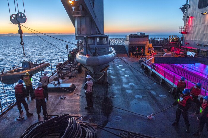 Sailors stand on the deck of a ship