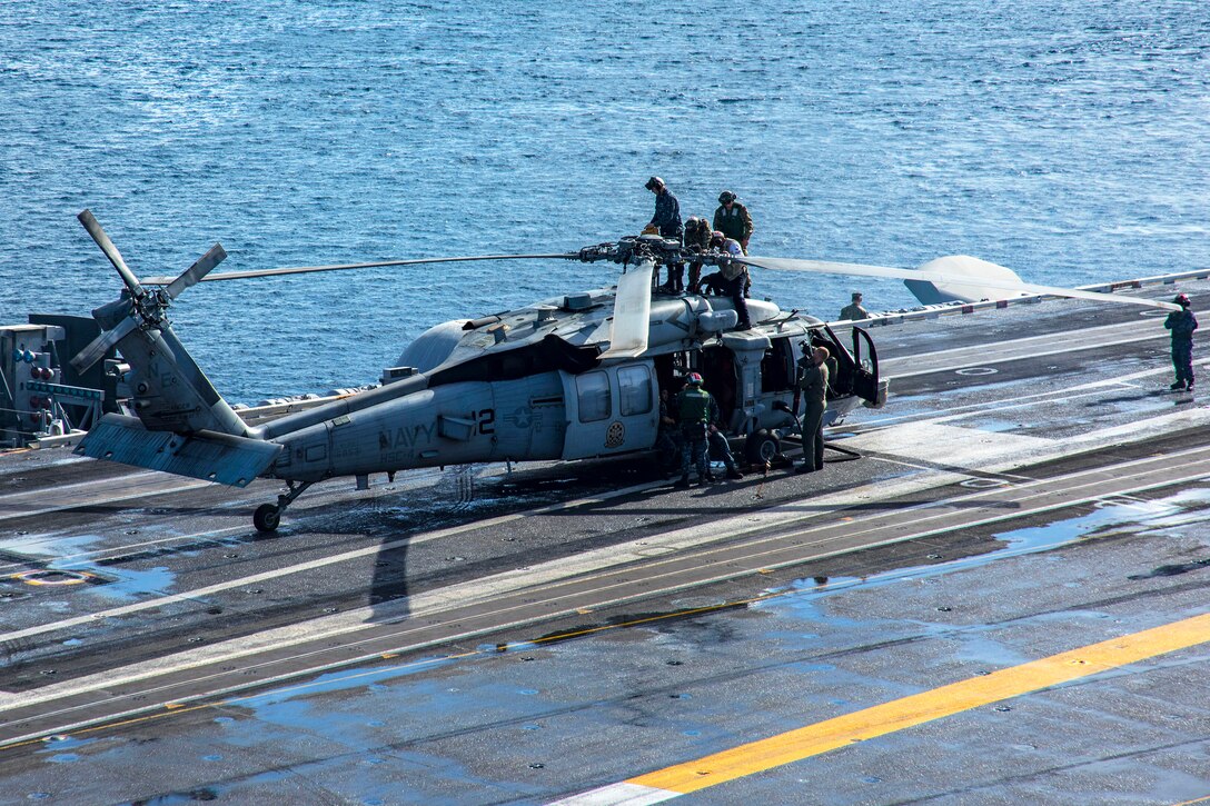 Sailors prepare an MH-60S Sea Hawk helicopter for flight operations on the flight deck of the aircraft carrier USS Carl Vinson.
