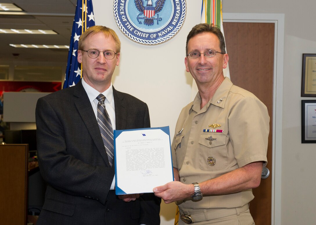 180129-N-YG220-044 ARLINGTON, Va. (Jan. 29, 2018) Rear Adm. David Hahn, chief of naval research (CNR), presents Dr. Gerald C. Manke with a Meritorious Service Award during a ceremony held at the Office of Naval Research. (U.S. Navy photo by Moraima Johnston/Released)
