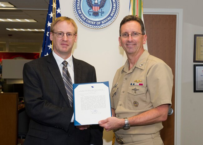 180129-N-YG220-044 ARLINGTON, Va. (Jan. 29, 2018) Rear Adm. David Hahn, chief of naval research (CNR), presents Dr. Gerald C. Manke with a Meritorious Service Award during a ceremony held at the Office of Naval Research. (U.S. Navy photo by Moraima Johnston/Released)