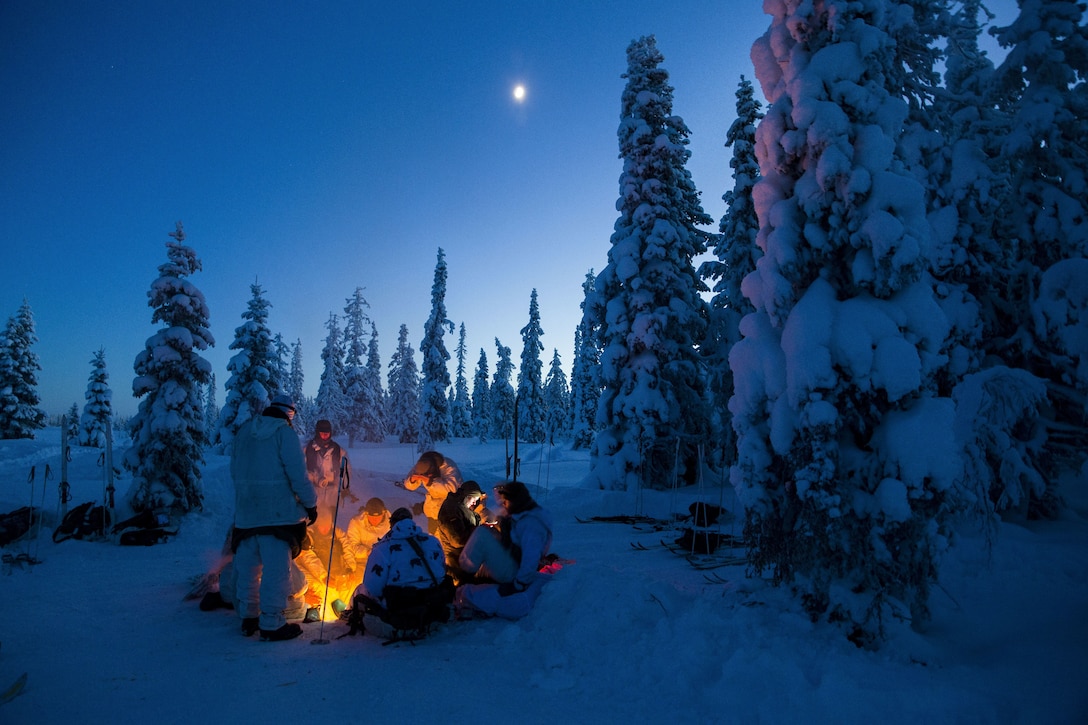 Participants of the Swedish Basic Winter Warfare Course rest and try to warm up in front of a fire during the course's culminating event in Arvidsjaur, Sweden, Jan. 23, 2018. Marines from the Black Sea Rotational Force and the 26th Marine Expeditionary Unit, along with troops from 9 other countries, participated in the Swedish Basic Winter Warfare Course. The course developed the participants’ capability to survive in cold-weather environment, march on skis, apply his or hers tactical skills at individual and squad levels, and to lead smaller units in winter warfare in subarctic winter conditions. (U.S. Marine Corps photo by SSgt. Marcin Platek/Released)