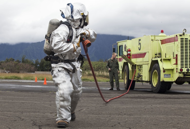 A U.S. Marine with Aircraft Rescue Fire Fighting (ARFF) unrolls a firehose from a P-19 Firefighting Vehicle during a wheel fire exercise at West Field, Marine Corps Air Station, Feb. 2, 2018. ARFF conducted a wheel fire exercise to improve proficiency in assessing and extinguishing a fire by utilizing the Mobile Aircraft Firefighting Training Device. (U.S. Marine Corps photo by Cpl. Jesus Sepulveda Torres)