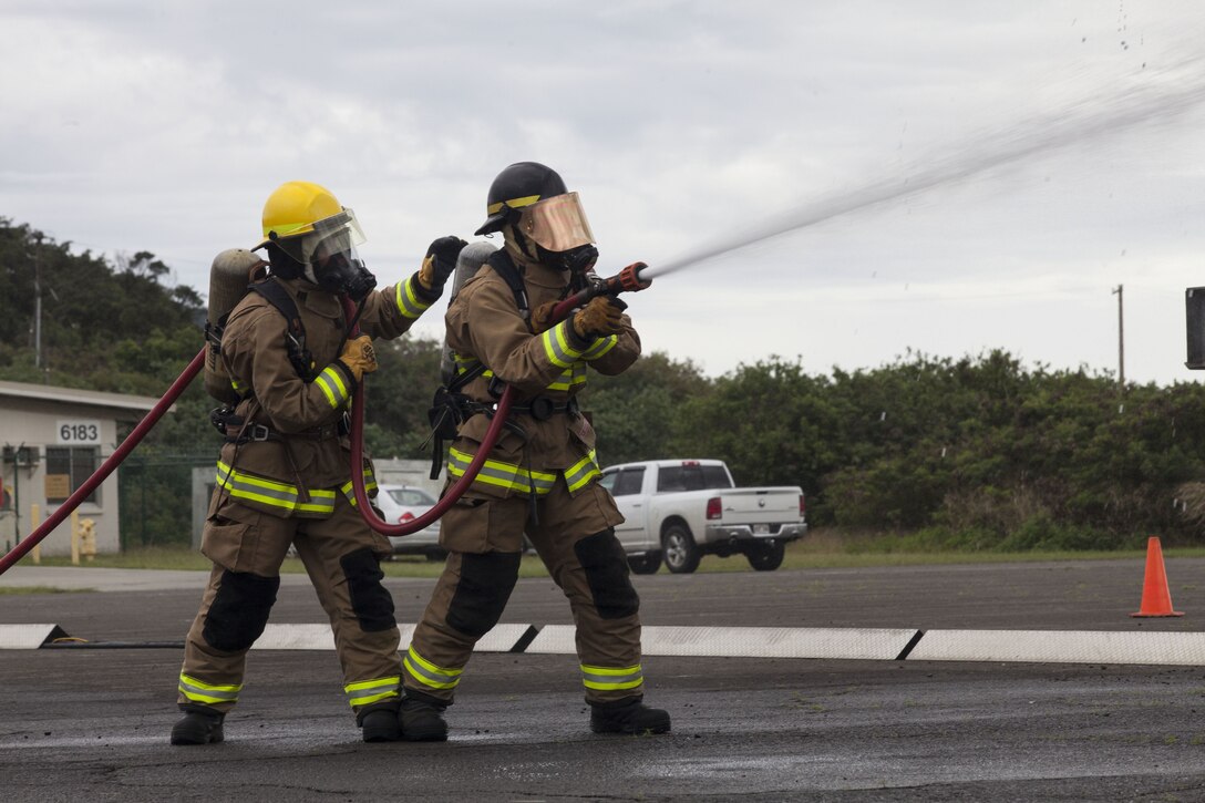 U.S. Marines with Aircraft Rescue Fire Fighting (ARFF) use a water hose on a training aircraft engulfed in flames during a wheel fire exercise at West Field, Marine Corps Air Station, Feb. 2, 2018. ARFF conducted a wheel fire exercise to improve proficiency in assessing and extinguishing a fire by utilizing the Mobile Aircraft Firefighting Training Device. (U.S. Marine Corps photo by Cpl. Jesus Sepulveda Torres)