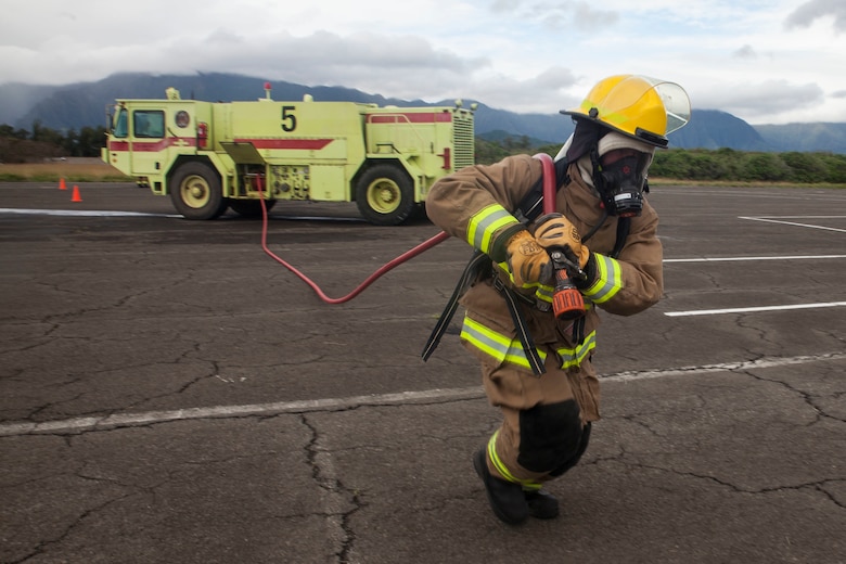 A U.S. Marine with Aircraft Rescue Fire Fighting (ARFF) unrolls a firehose from a P-19 Firefighting Vehicle during a wheel fire exercise at West Field, Marine Corps Air Station, Feb. 2, 2018. ARFF conducted a wheel fire exercise to improve proficiency in assessing and extinguishing a fire by utilizing the Mobile Aircraft Firefighting Training Device. (U.S. Marine Corps photo by Cpl. Jesus Sepulveda Torres)