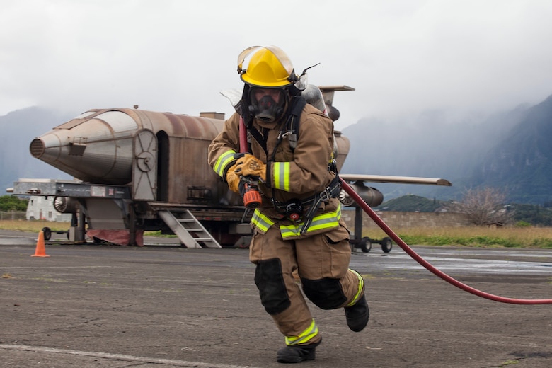 A U.S. Marine with Aircraft Rescue Fire Fighting (ARFF) unrolls a firehose during a wheel fire exercise at West Field, Marine Corps Air Station, Feb. 2, 2018. ARFF conducted a wheel fire exercise to improve proficiency in assessing and extinguishing a fire by utilizing the Mobile Aircraft Firefighting Training Device. (U.S. Marine Corps photo by Cpl. Jesus Sepulveda Torres)