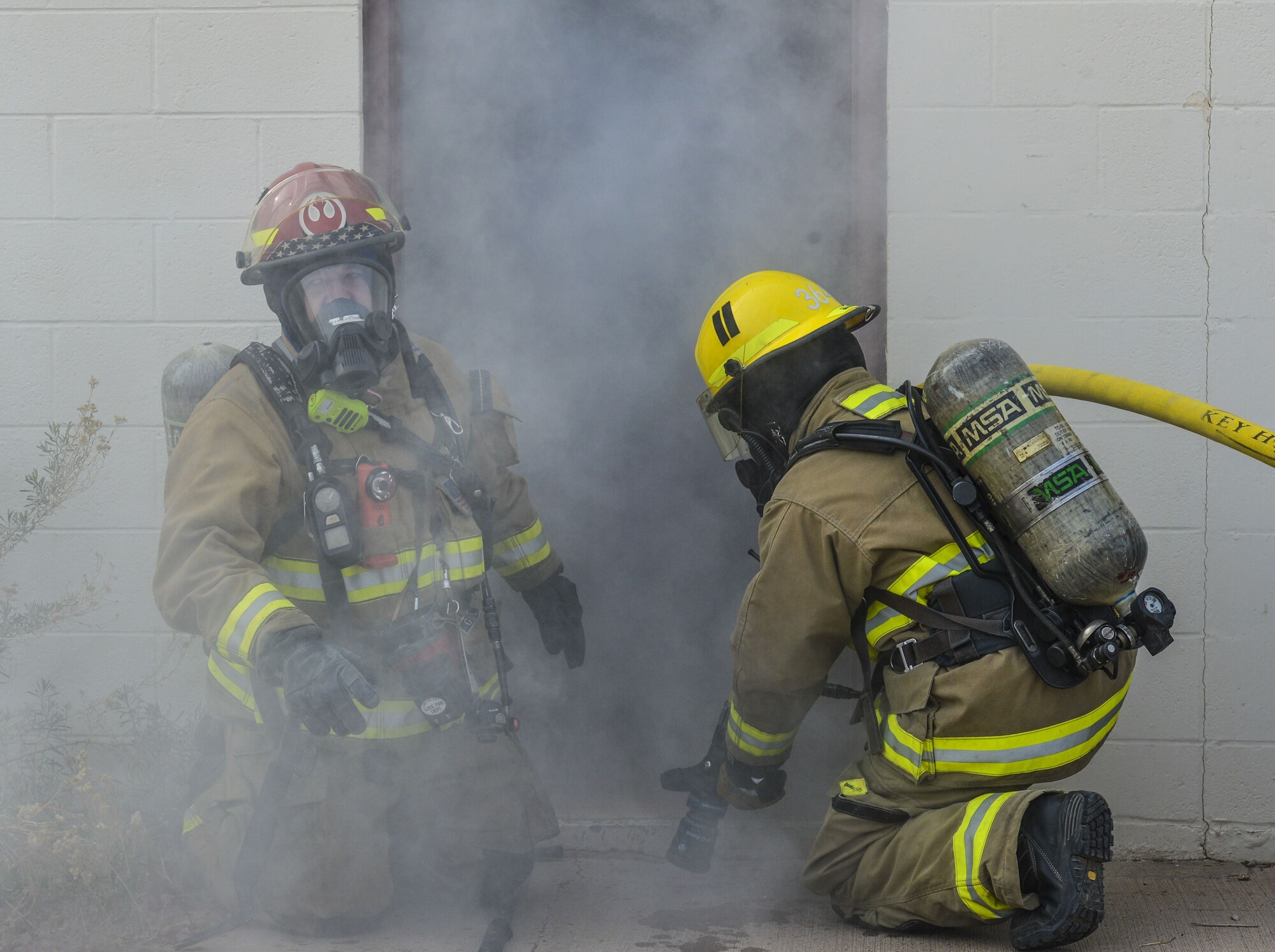 Airmen assigned to the 56th Civil Engineer Squadron prepare to enter a smoky building during structural firefighting training at Luke Air Force Base, Ariz., Jan. 16, 2018. The purpose of the training was to clear heat and smoke from a contained structure increasing chances of survival for trapped occupants. (U.S. Air Force photo/Airman 1st Class Caleb Worpel)