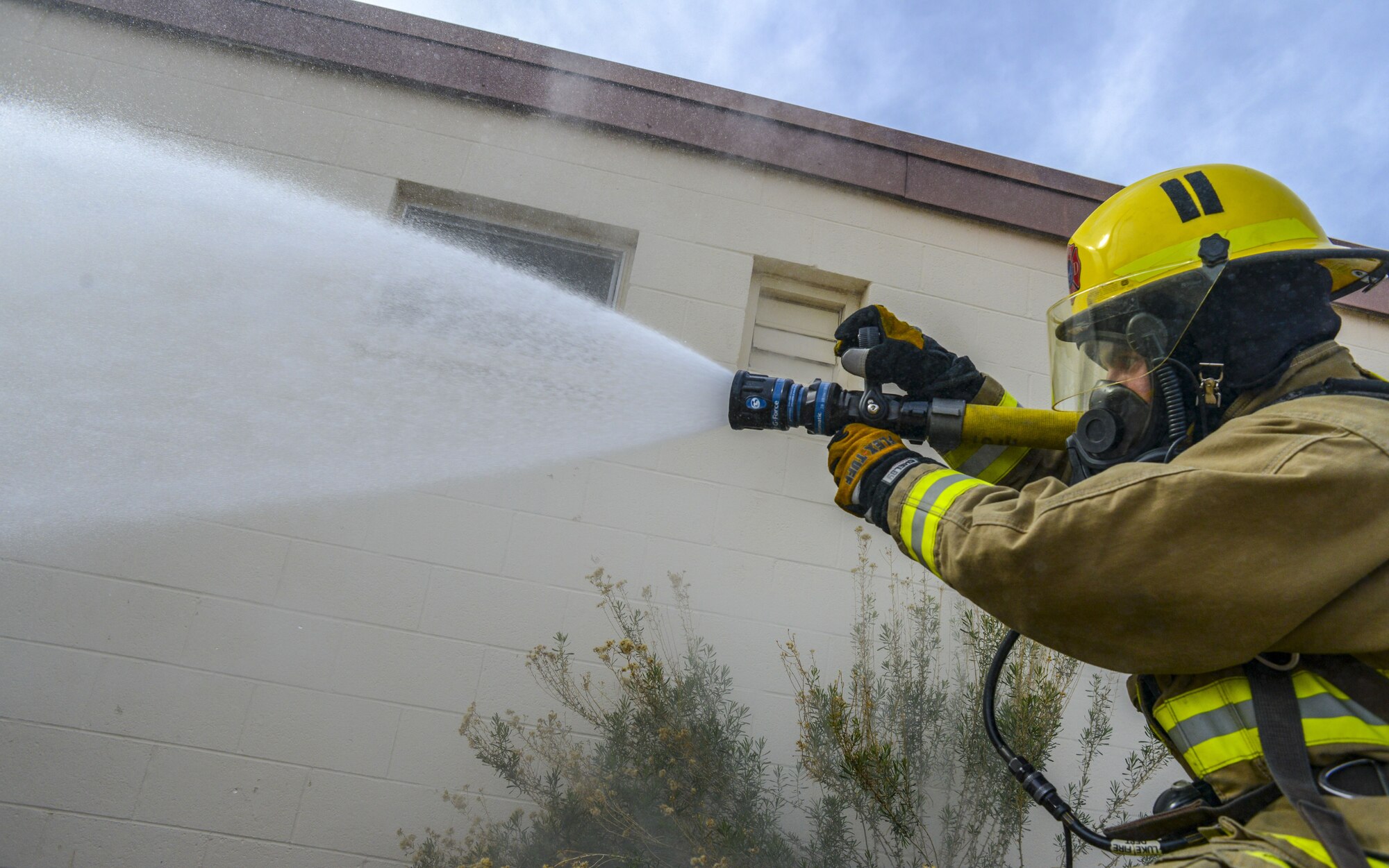 An Airman assigned to the 56th Civil Engineer Squadron uses a hose to put out a simulated fire during structural firefighting training at Luke Air Force Base, Ariz., Jan. 16, 2018. Firefighters use hands-on, realistic training scenarios to better prepare them for real-world situations. (U.S. Air Force photo/Airman 1st Class Caleb Worpel)