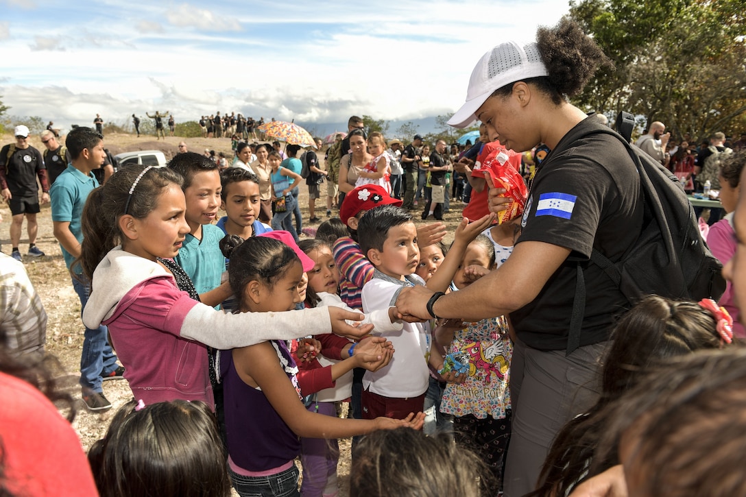 An airman hands out sweets to children in a village in Honduras.